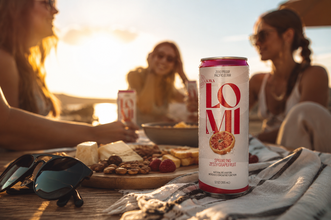 A can of Lomi Sparkling Zesty Grapefruit kava on a picnic table with snacks and friends enjoying time together in the background.