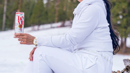 A model holding an alcohol-free Lomi Zesty Grapefruit drink outdoors in the snow, representing mindful drinking during Dry January.